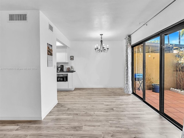 unfurnished dining area featuring light hardwood / wood-style floors and an inviting chandelier