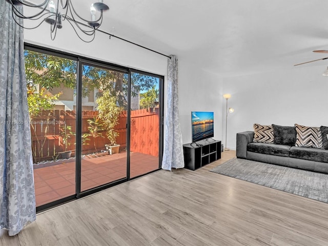 living room with light wood-type flooring and ceiling fan with notable chandelier