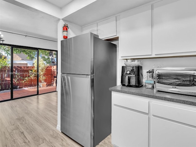 kitchen with white cabinetry, stainless steel refrigerator, and light hardwood / wood-style flooring