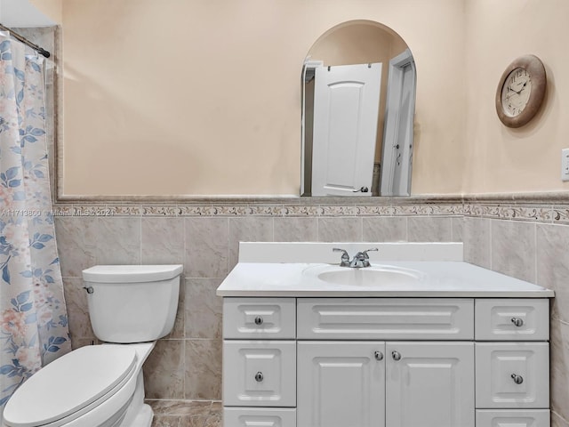 bathroom featuring a shower with shower curtain, vanity, toilet, and tile walls