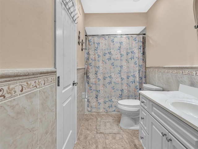 bathroom featuring vanity, toilet, and tile walls