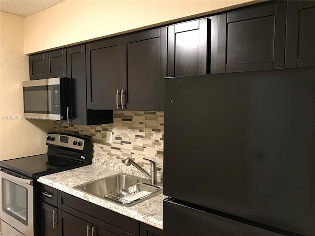 kitchen with light stone countertops, backsplash, stainless steel appliances, and sink