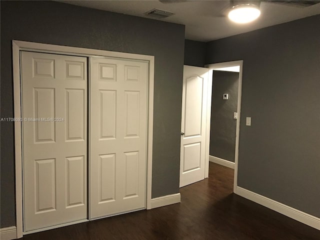 unfurnished bedroom with a closet and dark wood-type flooring