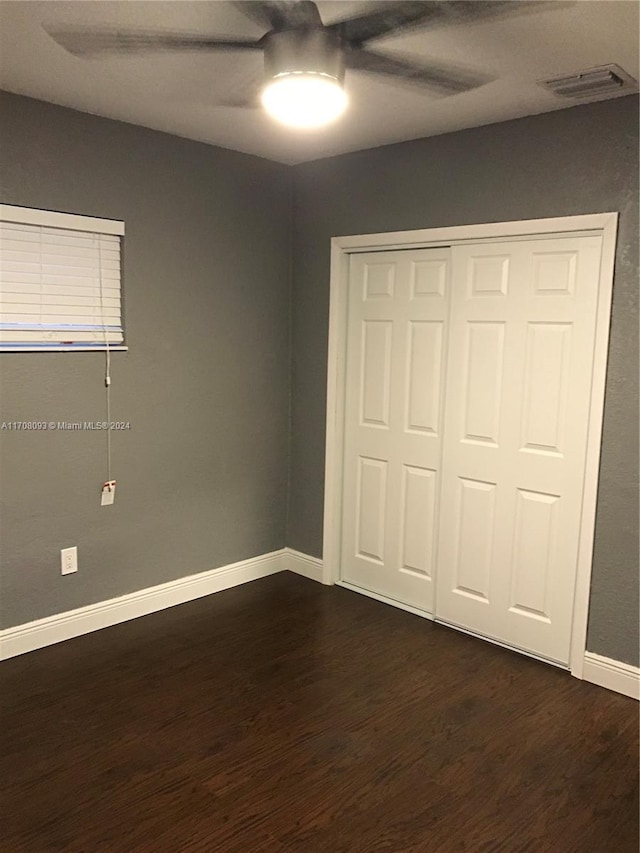 unfurnished bedroom with ceiling fan, dark hardwood / wood-style flooring, and a closet