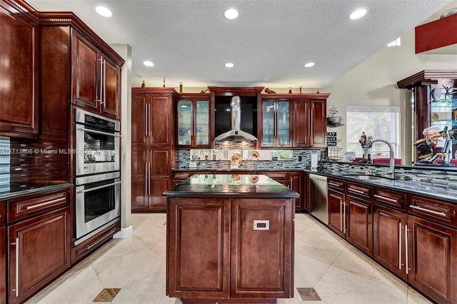 kitchen featuring tasteful backsplash, wall chimney exhaust hood, stainless steel appliances, sink, and a kitchen island