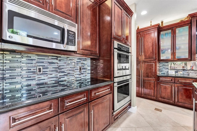 kitchen with appliances with stainless steel finishes, tasteful backsplash, and dark stone countertops