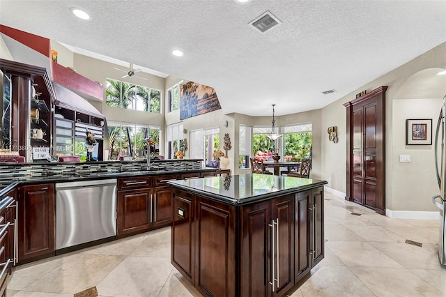 kitchen with ceiling fan, a center island, stainless steel dishwasher, pendant lighting, and a textured ceiling