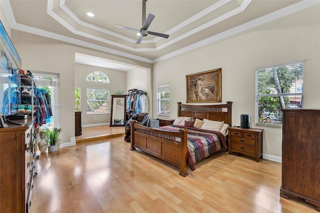 bedroom featuring ceiling fan, crown molding, a tray ceiling, and multiple windows