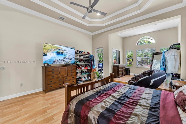 bedroom with hardwood / wood-style flooring, ceiling fan, a raised ceiling, and crown molding