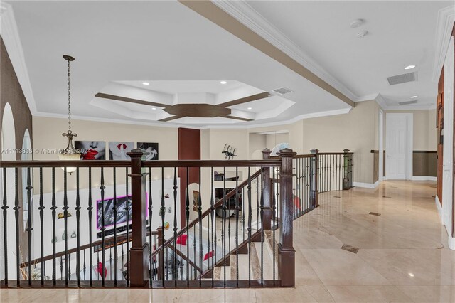 hall with a raised ceiling and ornamental molding