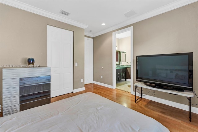 bedroom with wood-type flooring, crown molding, and connected bathroom