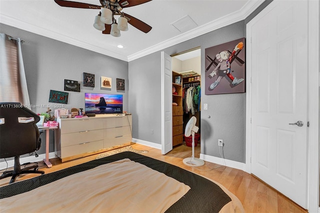 bedroom with ceiling fan, crown molding, a walk in closet, a closet, and light wood-type flooring