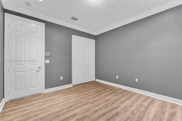 unfurnished bedroom with a textured ceiling, light hardwood / wood-style flooring, and ornamental molding