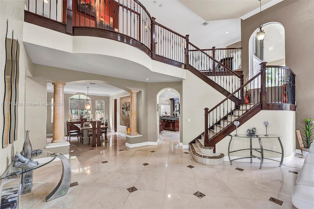 entrance foyer with ornate columns, plenty of natural light, and a towering ceiling