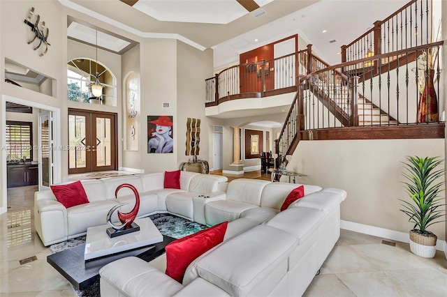 living room featuring ornate columns, crown molding, a high ceiling, and french doors