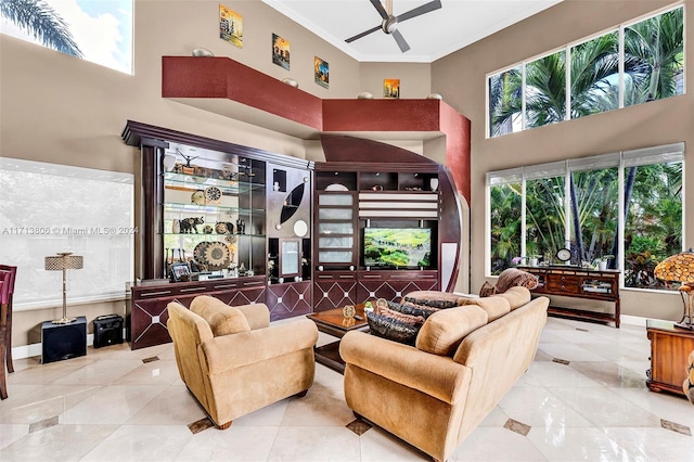 tiled living room with ceiling fan, a towering ceiling, and ornamental molding