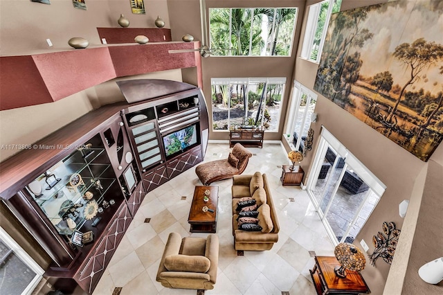 living room featuring tile patterned floors, a healthy amount of sunlight, and a towering ceiling