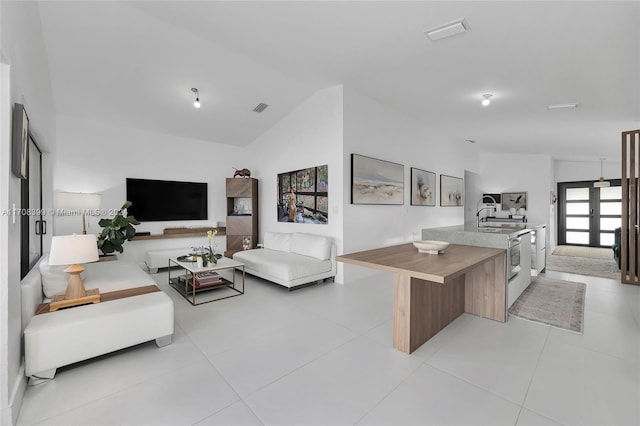 tiled living room featuring vaulted ceiling, sink, and french doors