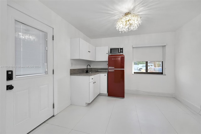 kitchen featuring white cabinetry, sink, an inviting chandelier, refrigerator, and light tile patterned floors