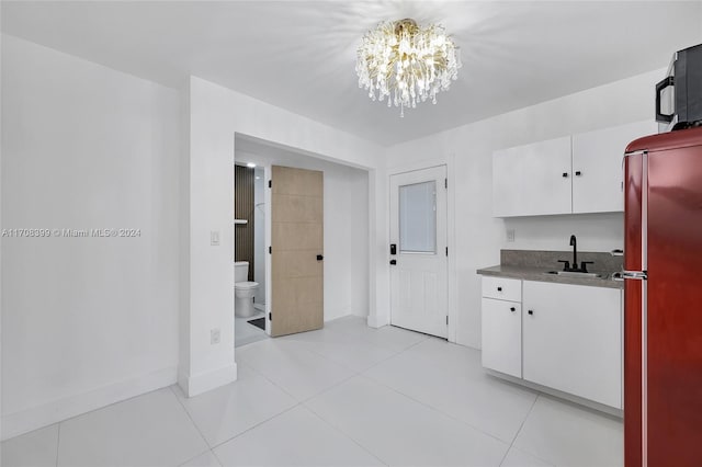 kitchen featuring white cabinetry, sink, stainless steel fridge, a chandelier, and light tile patterned flooring