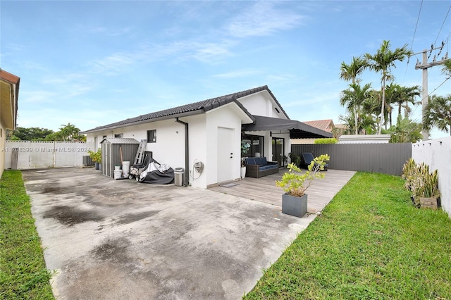 rear view of house featuring a lawn and a deck