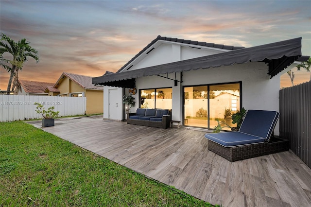 back house at dusk with a wooden deck