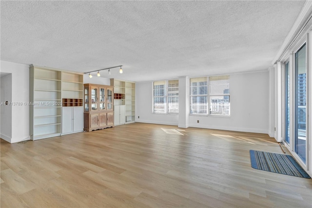 unfurnished living room with rail lighting, a textured ceiling, and light wood-type flooring