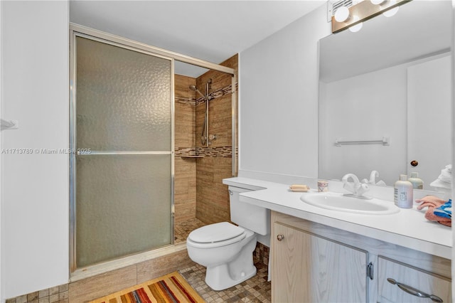 bathroom featuring tile patterned flooring, vanity, a shower with shower door, and toilet