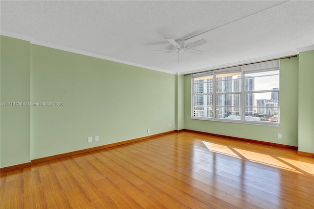 unfurnished room featuring ceiling fan, light hardwood / wood-style flooring, a textured ceiling, and ornamental molding