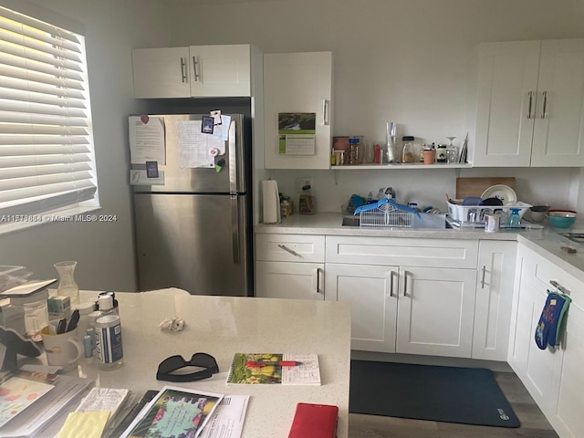 kitchen with stainless steel fridge and white cabinetry