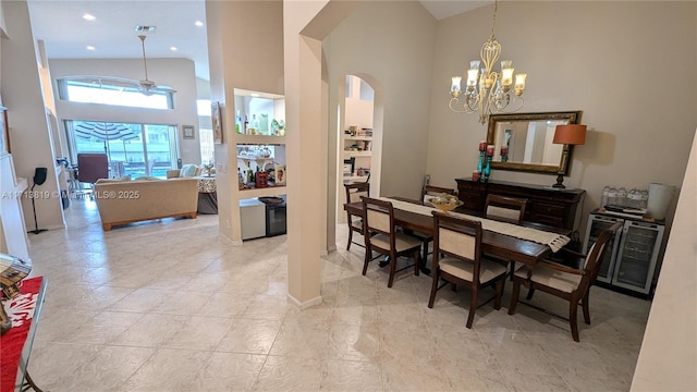 dining space featuring a towering ceiling and ceiling fan with notable chandelier