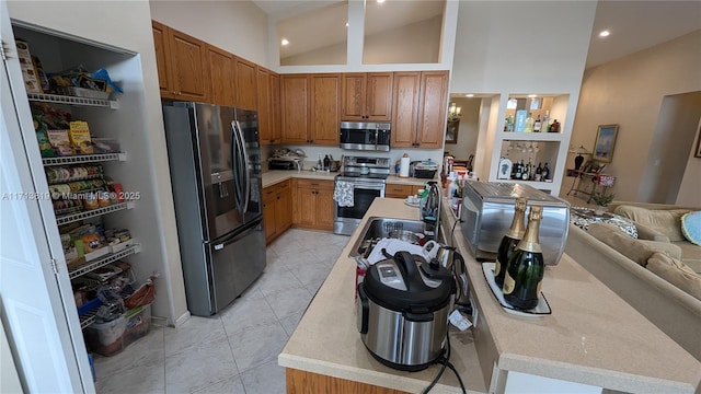 kitchen with light tile patterned flooring, sink, stainless steel appliances, and high vaulted ceiling