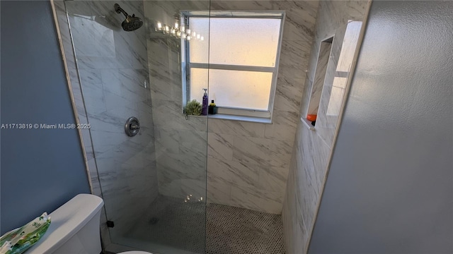 bathroom featuring tiled shower and toilet