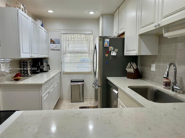 kitchen with white cabinets, light stone counters, dishwasher, and sink