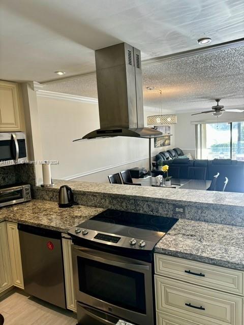 kitchen with island range hood, a textured ceiling, appliances with stainless steel finishes, and cream cabinets