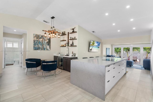 kitchen featuring white cabinetry, a center island, wine cooler, vaulted ceiling, and french doors