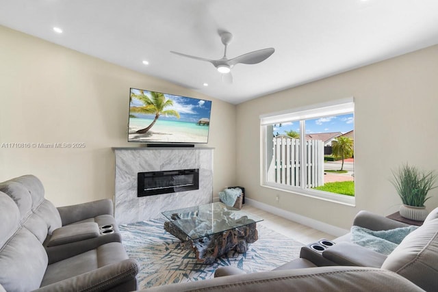 living room featuring ceiling fan, a premium fireplace, vaulted ceiling, and light hardwood / wood-style flooring