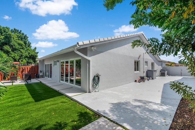 back of property with cooling unit, a patio area, and a lawn