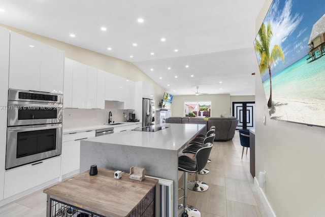 kitchen featuring a breakfast bar, sink, white cabinetry, a kitchen island, and stainless steel appliances