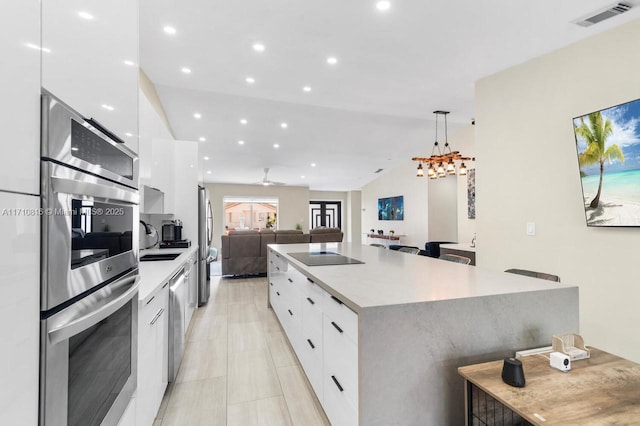 kitchen with decorative light fixtures, white cabinets, and a spacious island