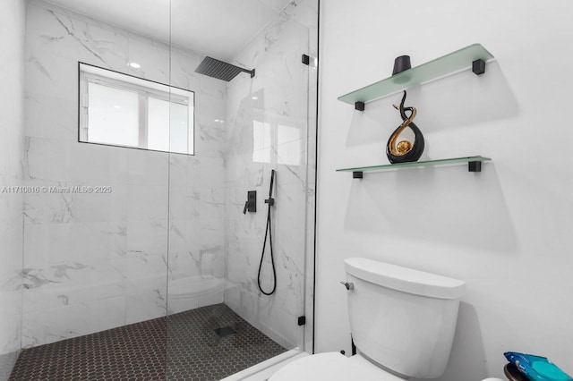 bathroom with a tile shower and toilet