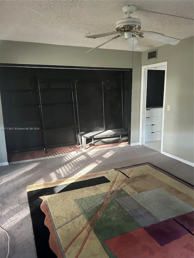 unfurnished bedroom featuring carpet flooring, ceiling fan, and a textured ceiling