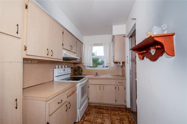 kitchen featuring white electric range, sink, and cream cabinets