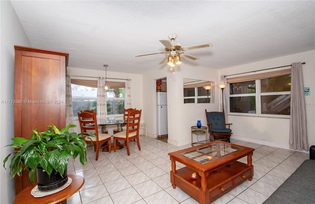 tiled living room with ceiling fan and a textured ceiling