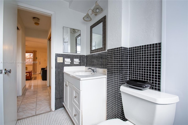 bathroom with tile patterned floors, vanity, tile walls, and toilet