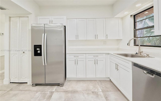 kitchen with light tile patterned floors, white cabinetry, sink, and appliances with stainless steel finishes