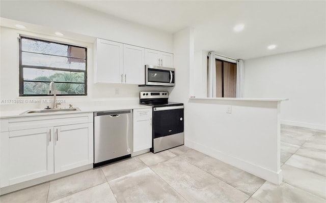 kitchen featuring white cabinets, appliances with stainless steel finishes, kitchen peninsula, and sink