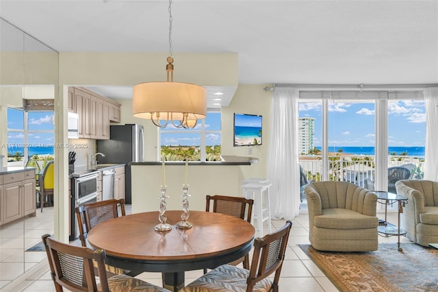 dining area featuring a water view and light tile patterned flooring