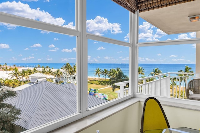 sunroom featuring a water view and a beach view