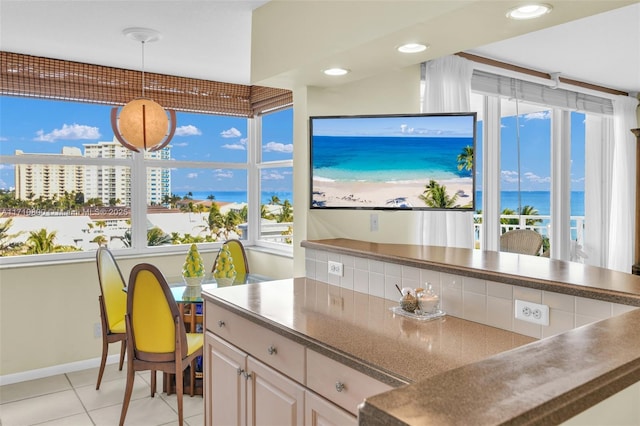 kitchen with light tile patterned flooring, backsplash, decorative light fixtures, and a water view